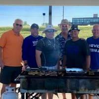 6 football alumni pose for a group picture by the grills